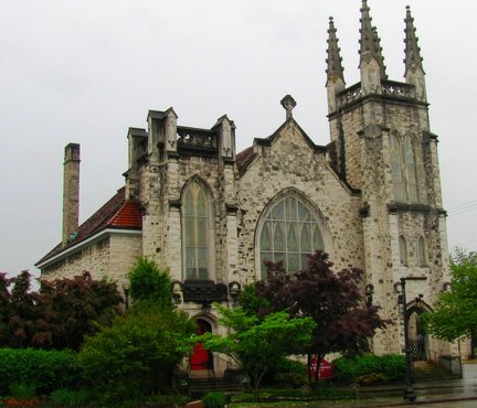 A beautiful picture of Saint John's Lutheran church from the outside. Gothic building with green trees and bushes all around